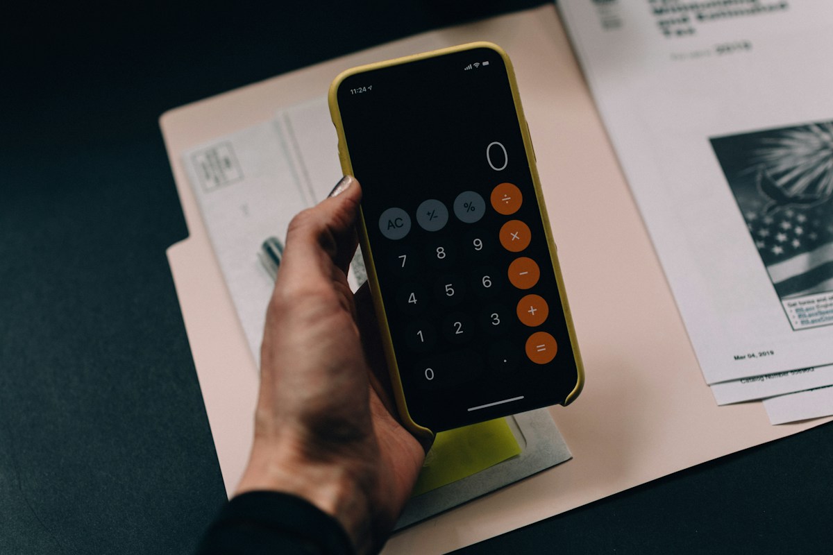 Calculator app open beside financial paperwork